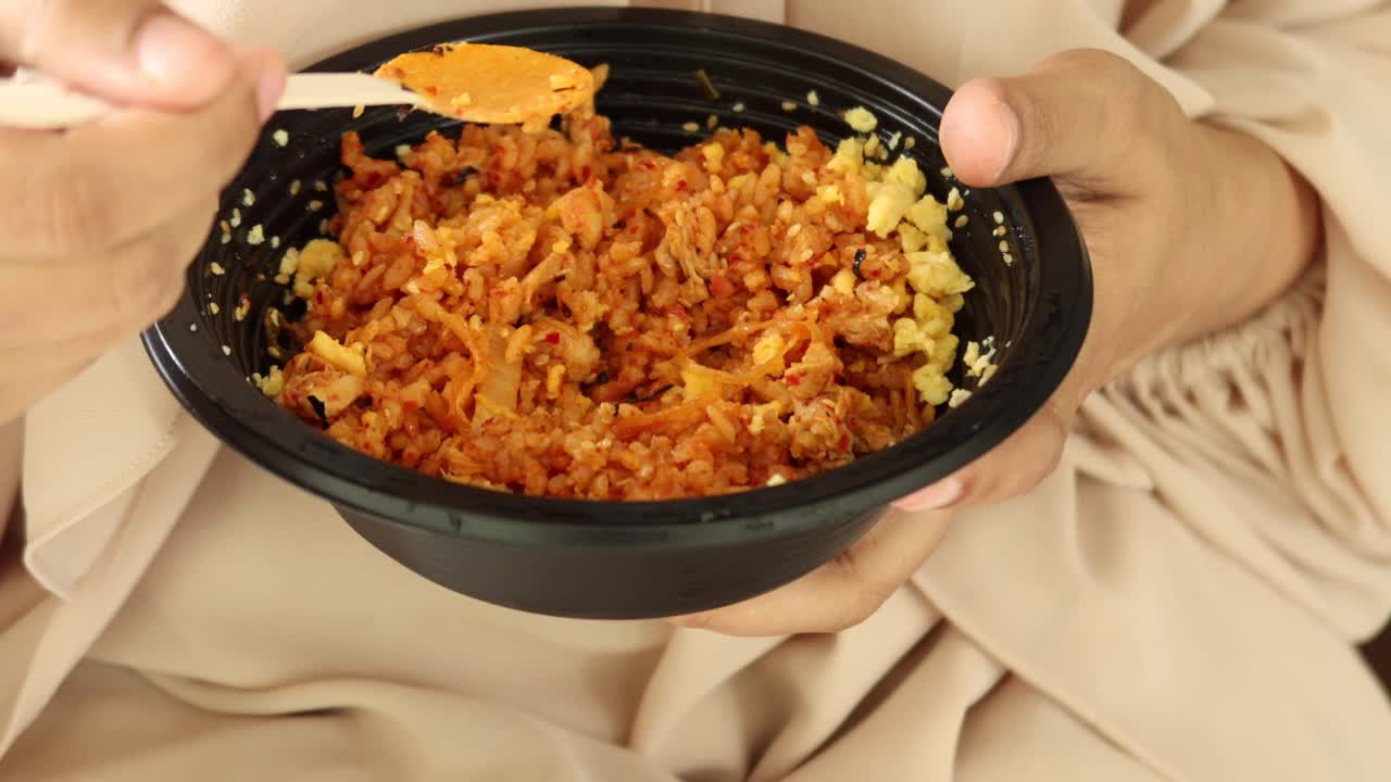 una mujer comiendo un delicioso arroz frito de kimchi.