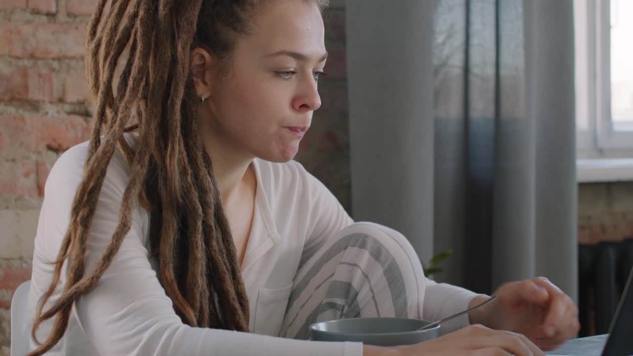 Female Freelancer Working While Eating Cereal