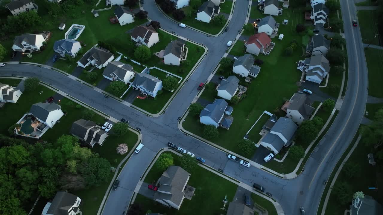 Classic American suburban neighborhood during spring season dusk, with neatly lined houses, tree-filled yards and winding streets. Pennsylvania, United States. Aerial Top down shot.