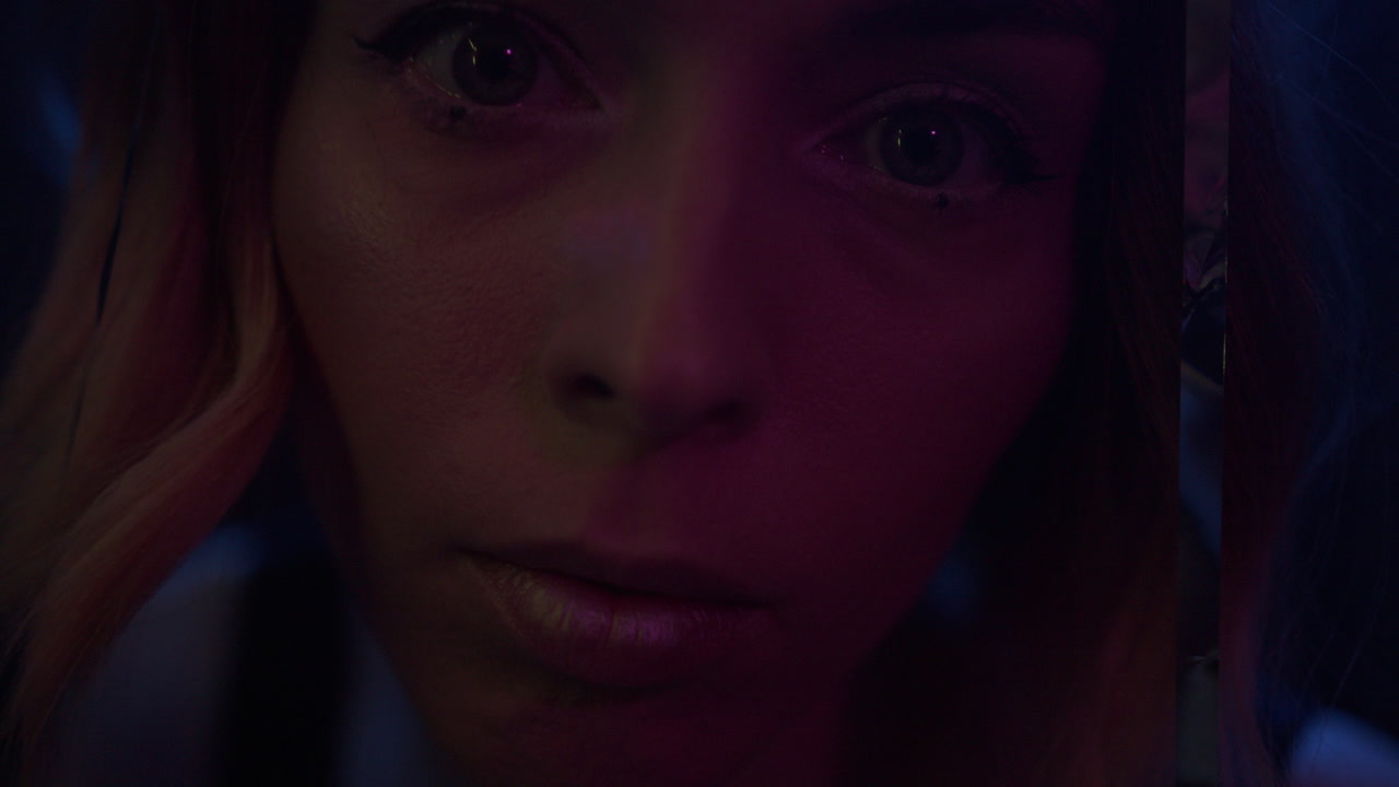 A young woman's face appears through glittering curtain