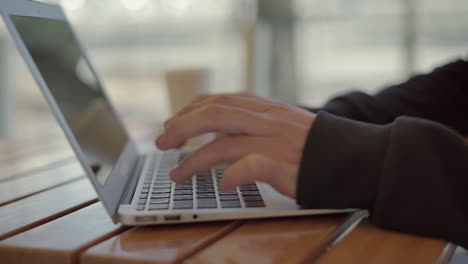 manos masculinas usando una computadora portátil en una mesa de madera