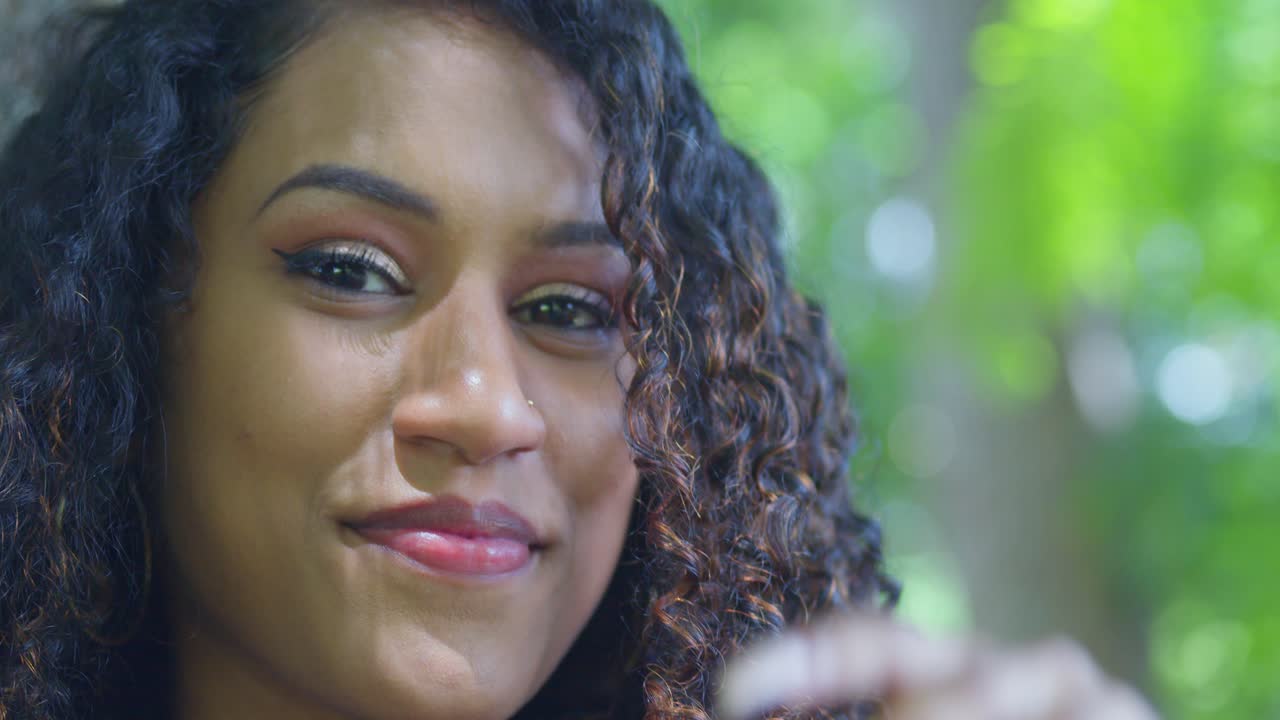 Close-up facial de uma modelo indiana com cabelo cacheado e um piercing no nariz