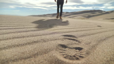 explorer walking away from camera leaving footprints in the sand in the desert