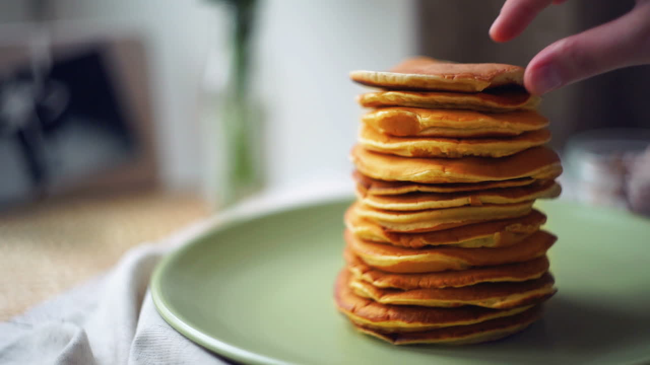 postre para el desayuno de la mañana. el hombre toma panqueque de la pila de panqueque