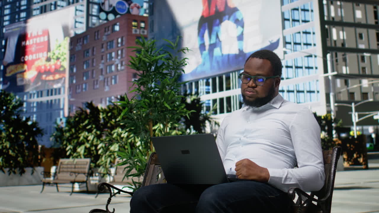 Afroamerikansk person frustrerad och stressad som arbetar online från en bänk
