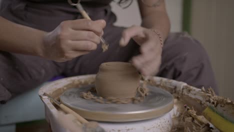 close-up of hands shaping pottery on a spinning wheel, focus on the creation process