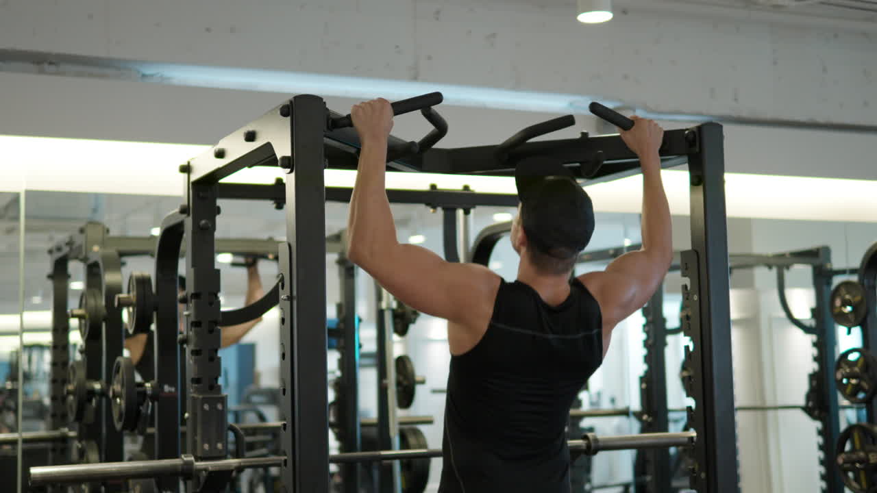 hombre adulto en forma haciendo pullups en el gimnasio
