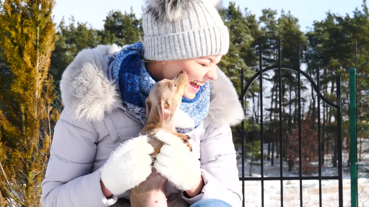 mujer jugando con su pequeño perro fuera del invierno