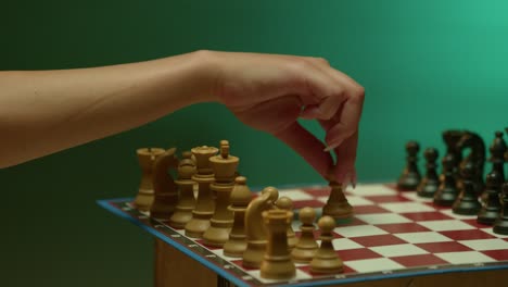 hand moving chess piece on a board in a dark room