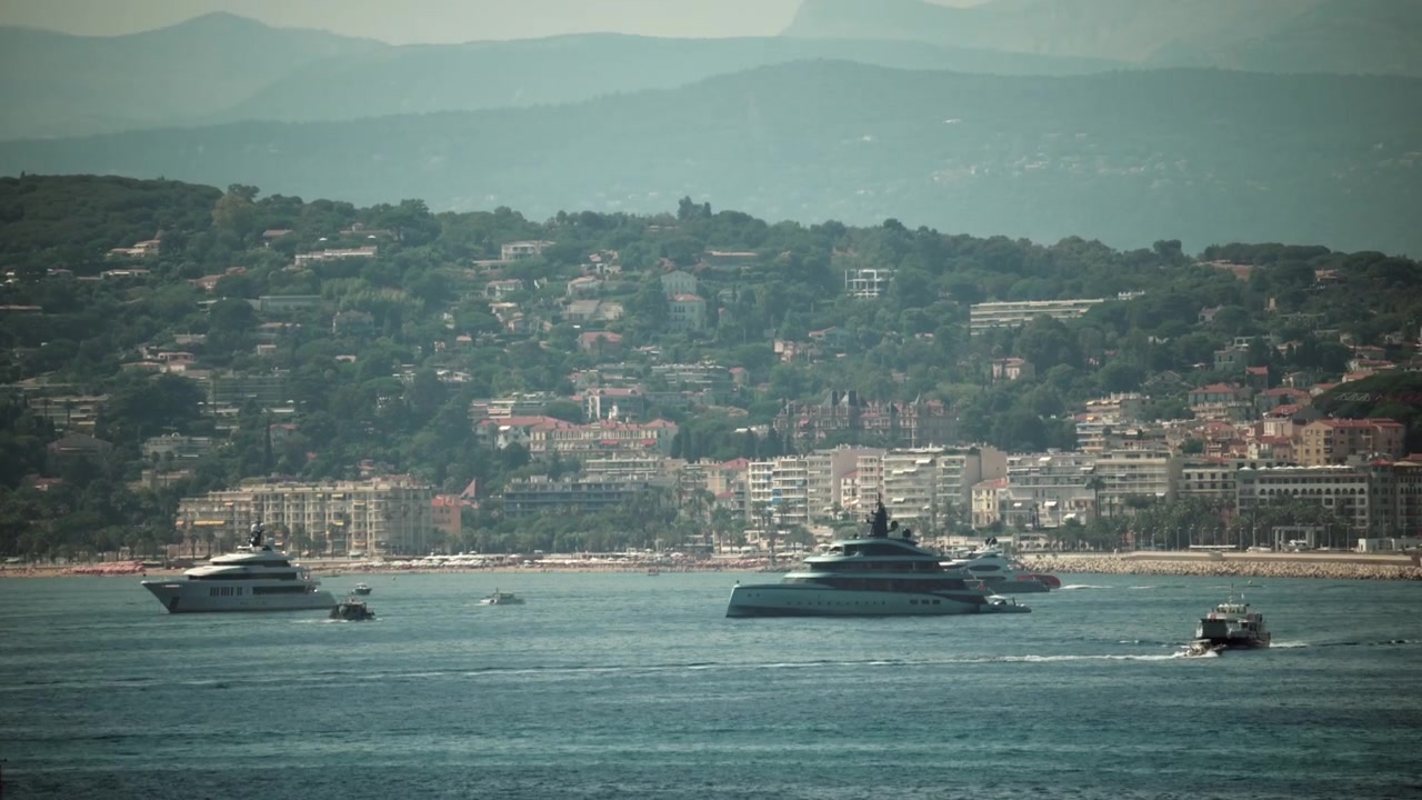 Superyacht di lusso che riposano nel Mar Mediterraneo con l'elegante costa di Cannes e le colline residenziali sullo sfondo