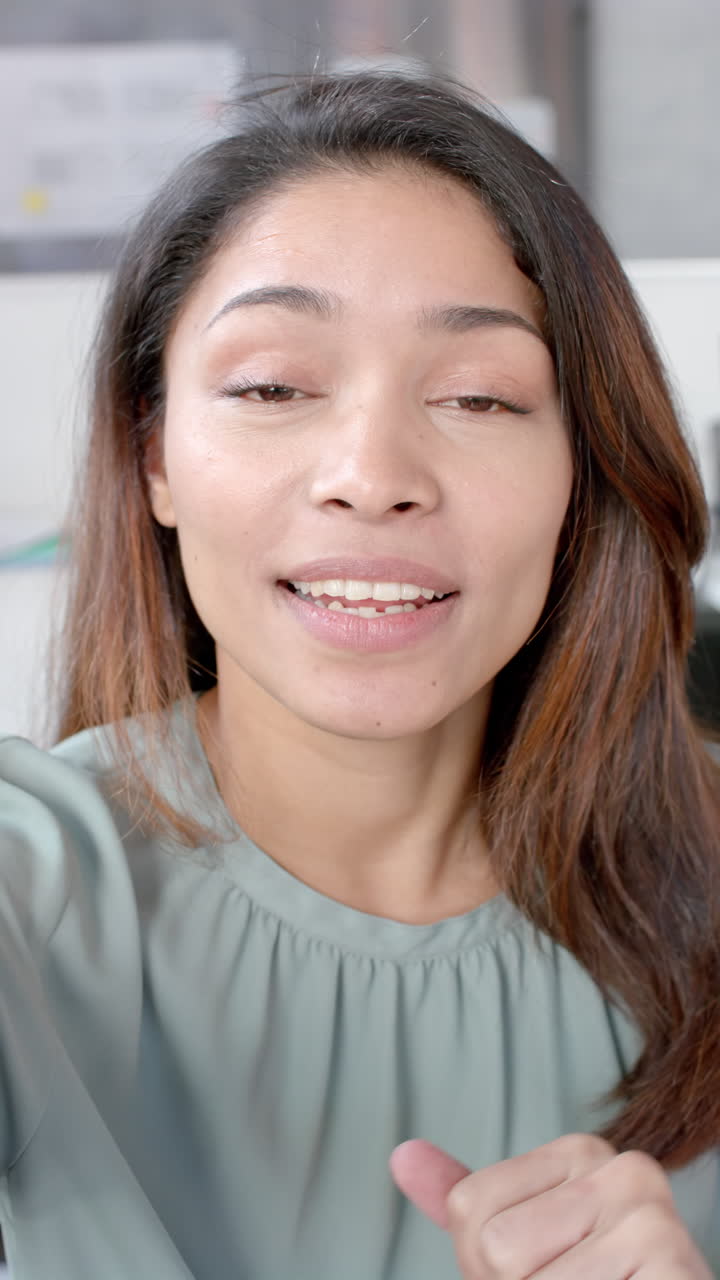 Vertical video of portrait of biracial businesswoman having video call in slow motion