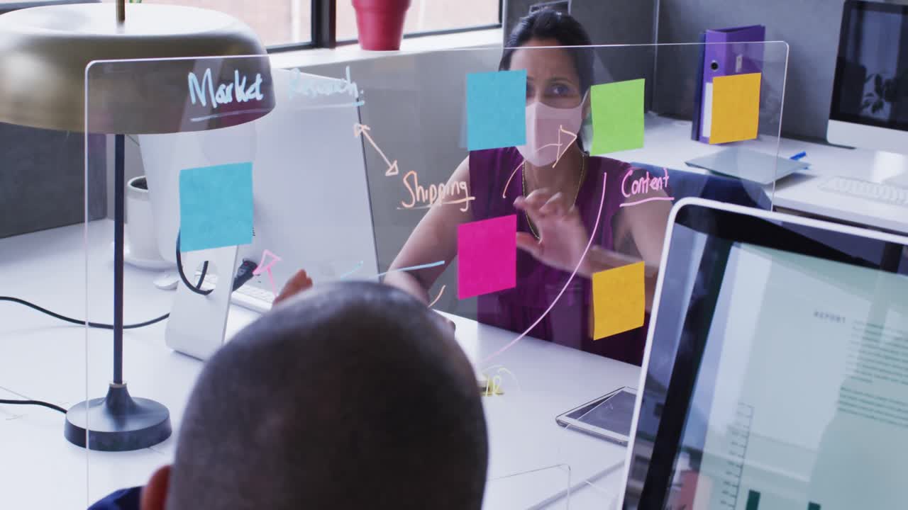 diversos colegas de negocios que usan máscaras faciales usando computadoras hablando en la oficina