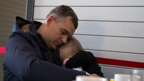 niña pequeña durmiendo en las manos de su padre en el aeropuerto