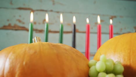 Composition-of-seven-lit-candles-and-halloween-pumpkins-and-grapes