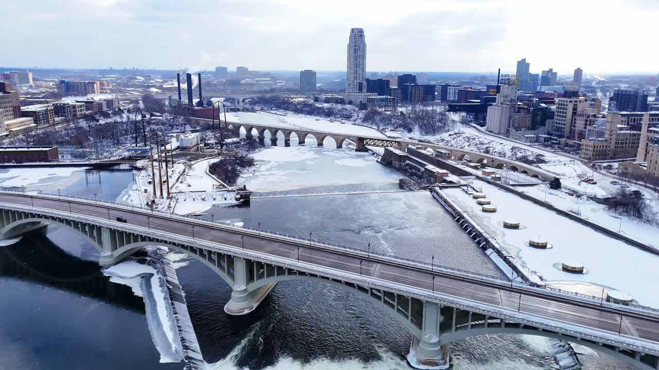 Minneapolis silüetinin kışın donmuş Mississippi Nehri ve kemerli köprülerle havadan görünümü