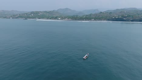 vista aérea en cámara lenta de un pequeño barco de pesca en el tunco el salvador