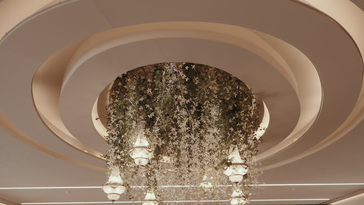Floral wedding chandelier installation with cascading greenery hanging from circular ceiling design