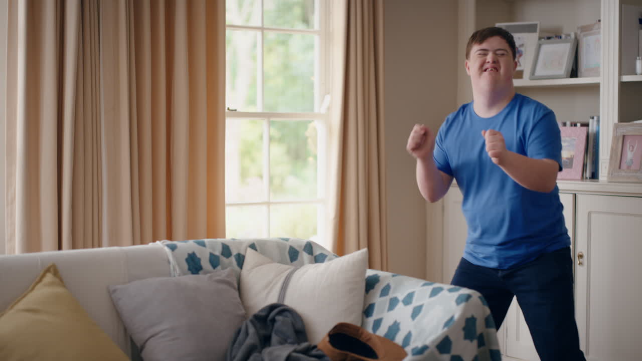 funny teenager boy with down syndrome dancing in living room special needs kid having fun celebrating with silly dance moves enjoying happy weekend at home 4k