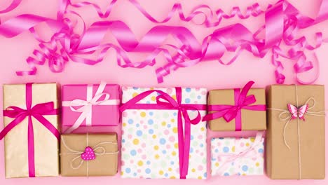 los regalos aparecen y desaparecen rápidamente bajo cintas rosas.