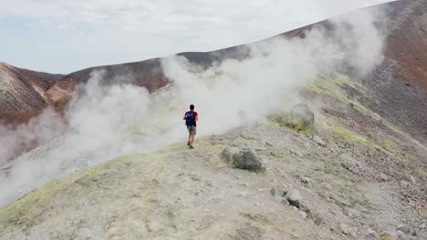 hombre caminando en el volcán y caminando a través de humos sulfúricos. paisaje volcánico de la isla del volcán