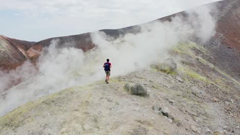 man hiking on volcano and walking trough sulfuric smokes. volcanic landscape of volcano island