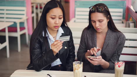 two women discussing a payment at a cafe