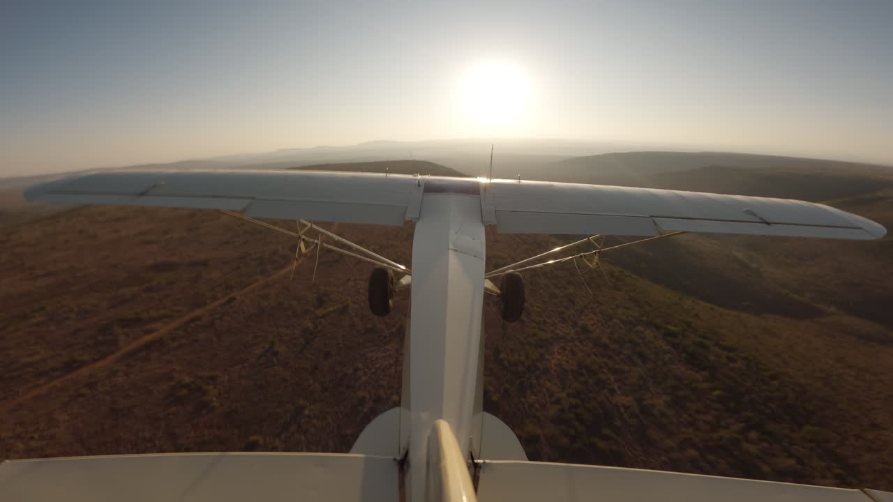 Aereo che vola sopra colline, dighe e praterie della savana