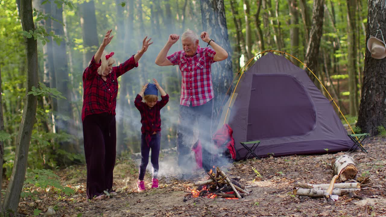 los abuelos y la nieta se divierten acampando en el bosque.