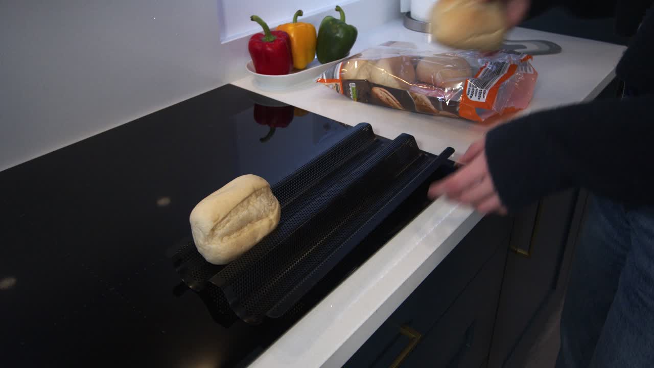 female model putting part baked rolls on a baking tray in a modern kitchen