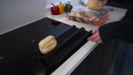 female model putting part baked rolls on a baking tray in a modern kitchen