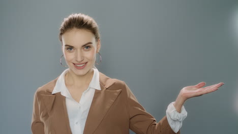 Junge-Geschäftsfrau-Präsentiert-Produkt-Auf-Grauem-Hintergrund