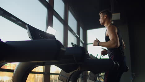 Jóvenes-Atléticos,-Hombres-Y-Mujeres,-Haciendo-Ejercicio-Y-Corriendo-En-Cinta-En-Un-Gimnasio-Deportivo.-Cámara-Lenta-Cerca-De-Una-Gran-Ventana-Panorámica