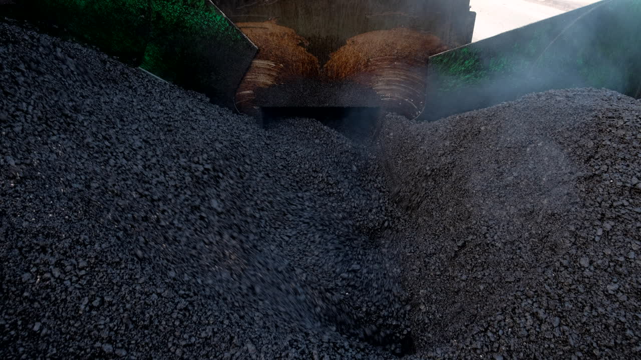 An asphalt paving machine pulls in hot asphalt and prepares it for placement on the road