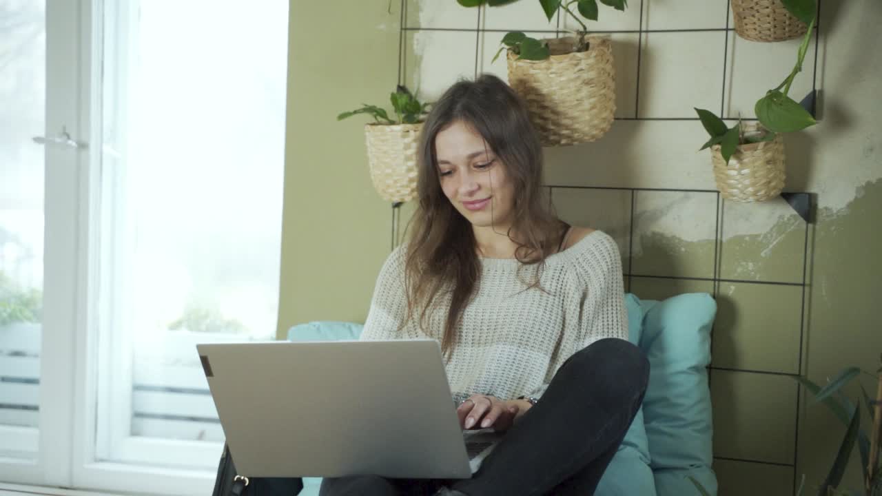 Estudiante europea de cabello oscuro trabajando en su portátil moderno y vistiendo ropa de invierno