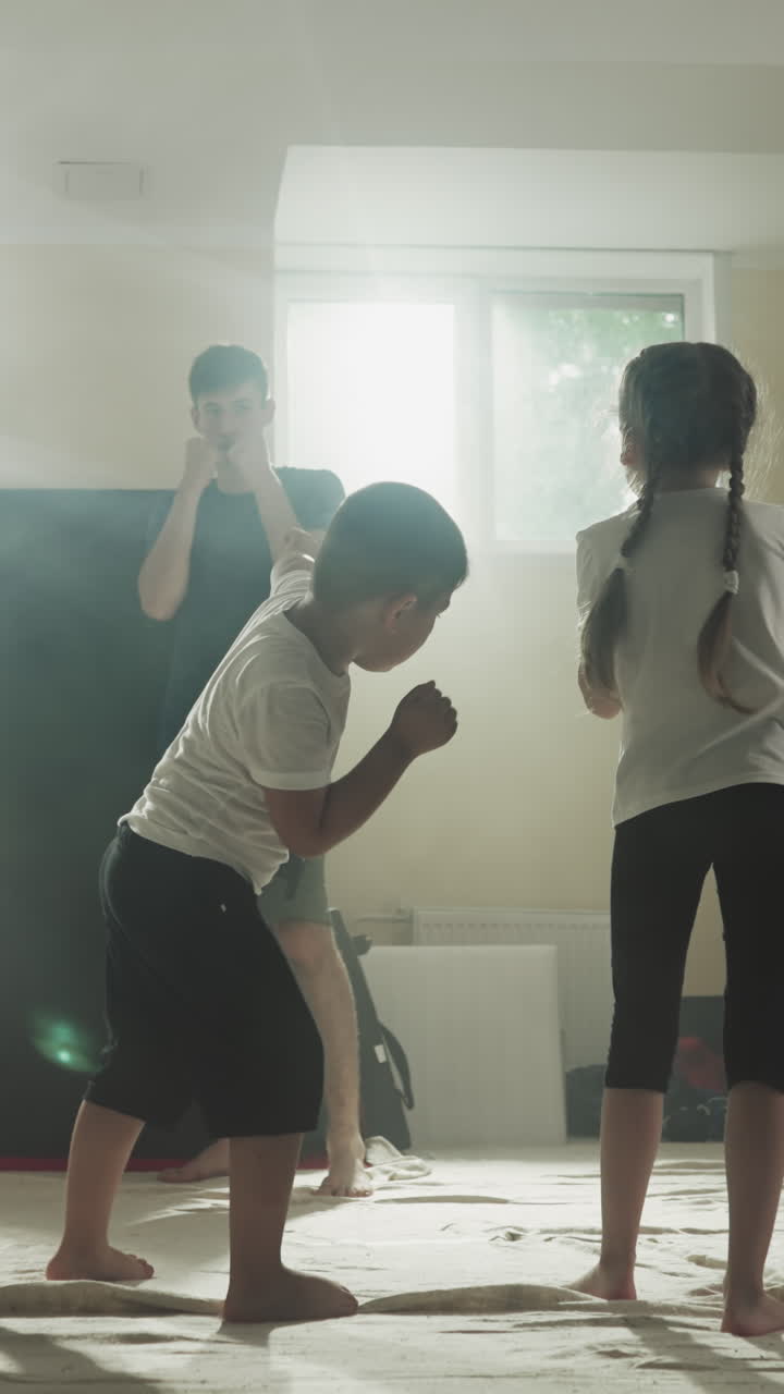 마셜 아트 학교에서 아이들에게 주먹을 는 것을 보여주는 트레이너. 주니어 운동선수들은 체육관에서 스로우 모션에서 마스터를 따라 손으로 타격을 반복합니다. 건강한 활동