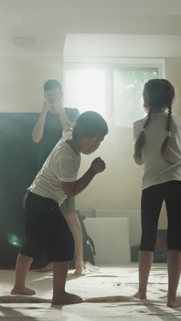 el entrenador demuestra golpes a los niños en la escuela de artes marciales. los atletas junior repiten golpes con las manos siguiendo al maestro en el gimnasio en cámara lenta. actividad saludable