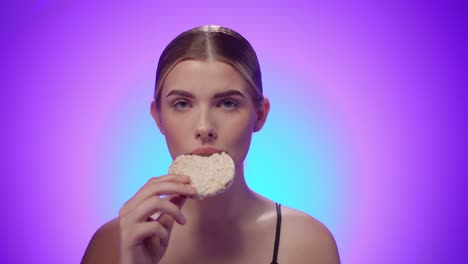 Serious-fitness-model-eats-a-rice-cake-to-stay-in-shape,-studio-shot