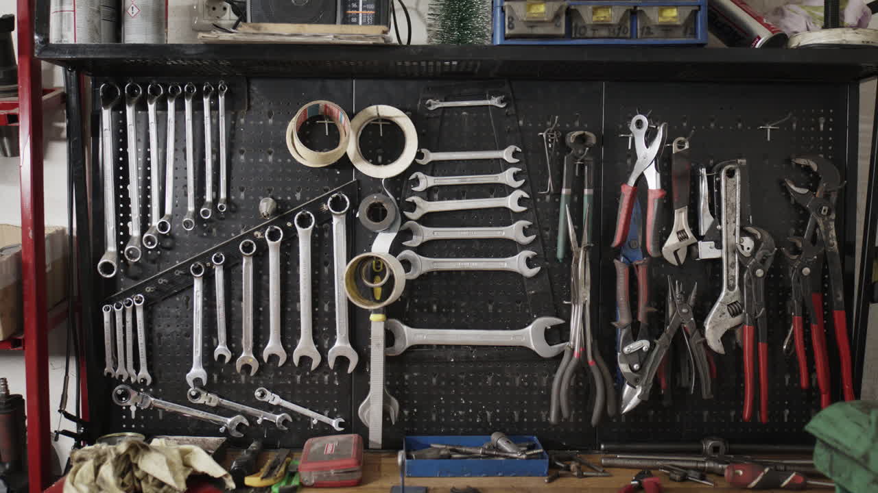 A well-organized mechanic's workshop tool board featuring a collection of hanging wrenches, pliers, and hardware