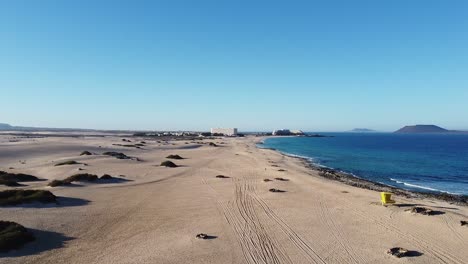 Panoramaaufnahme-Eines-Leeren,-Einsamen-Sandstrandes-Mit-Kleinen-Büschen-Am-Atlantik-Im-Sanften-Morgenlicht,-Tief-Fliegend