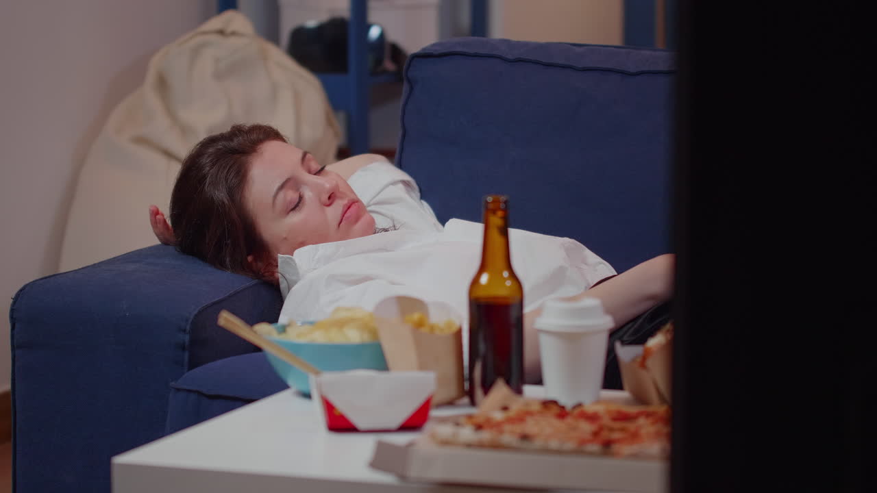 Close up of tired adult laying on couch with TV remote in hand