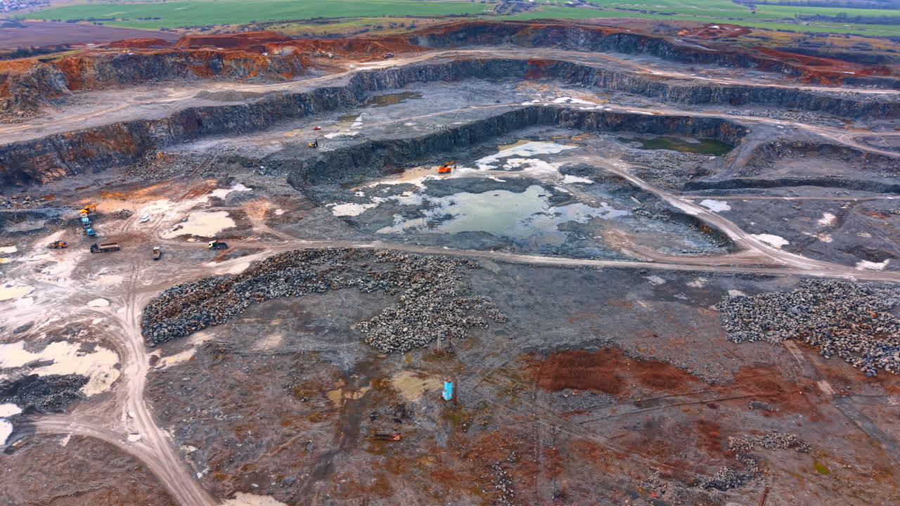 Large excavation at site. Heavy machines work at a large construction site where land is being excavated and shaped for new development