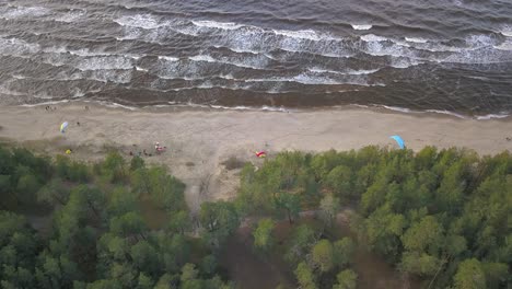 toma aérea de un grupo de parapente tratando de despegar en una playa en letonia