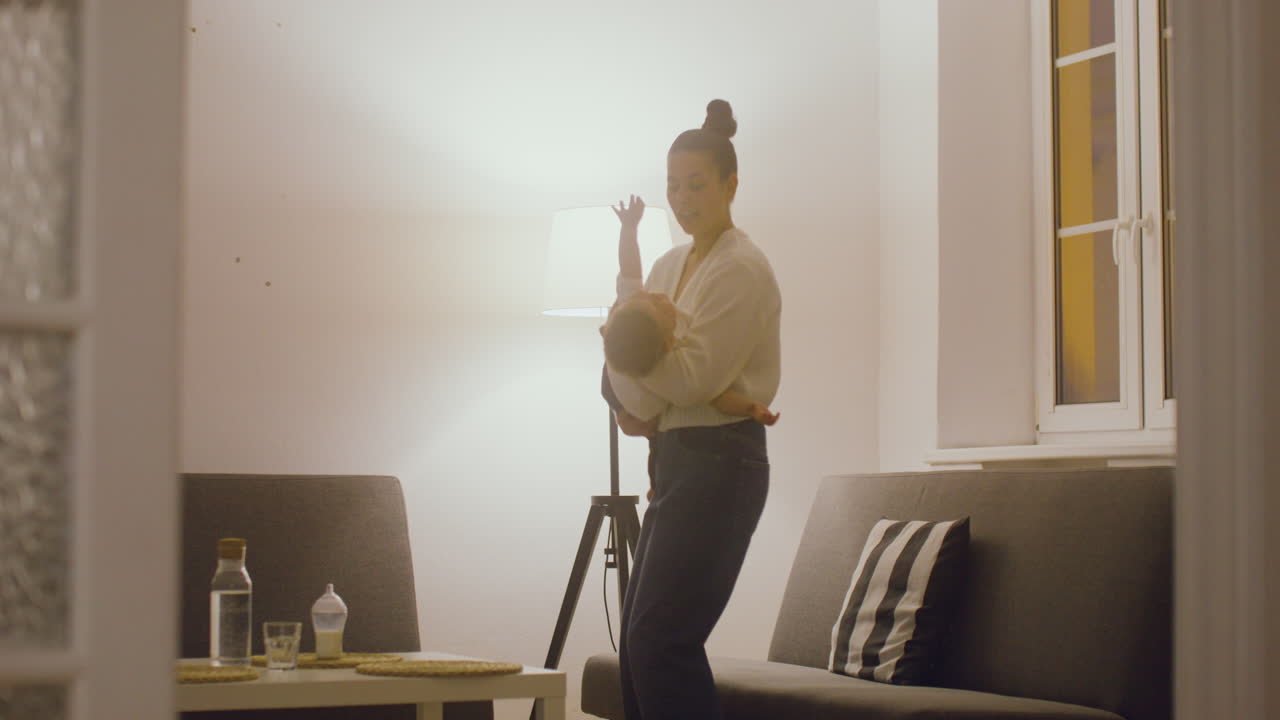 joven madre amamantando a su bebé mientras se sienta en el sofá en la sala de estar en casa