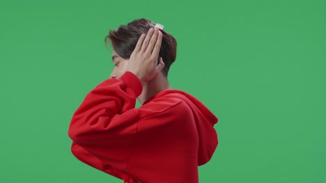 side view of asian transgender male listening to music with headphones and dancing in the green screen studio