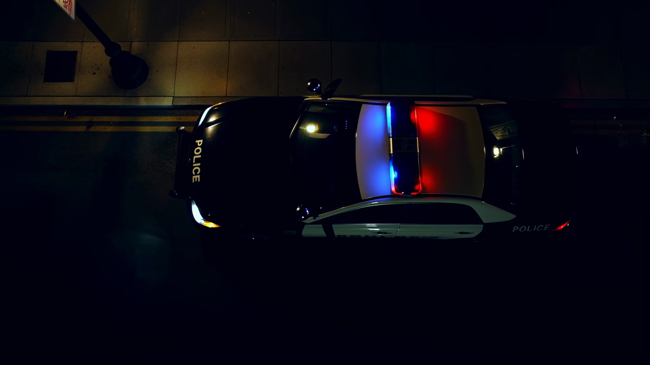 Overhead Police Car With Flashing Lights On Empty Urban Street At Night, Blue And Red Roof Lights Pulse,