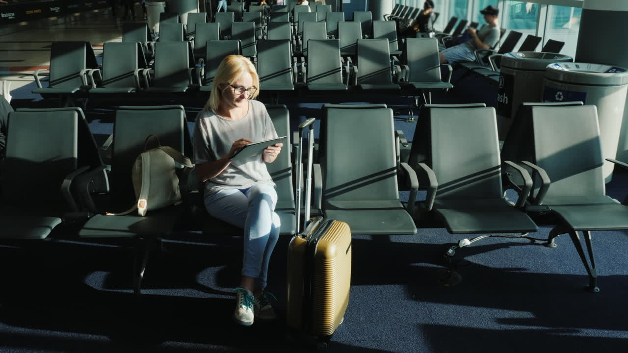 mujer usa tableta en la puerta del aeropuerto