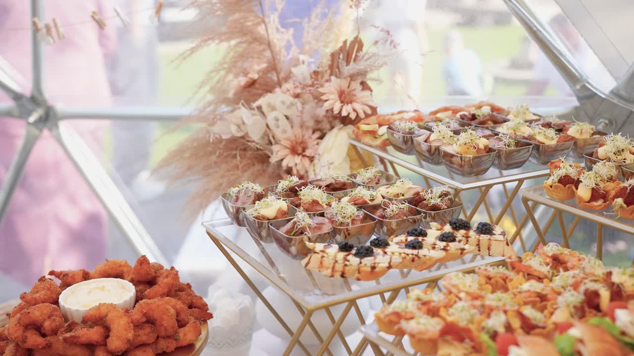 Stylish buffet display featuring assorted gourmet canapés, croissants, and crispy fried chicken with dip, arranged on elegant golden trays at a festive event celebration