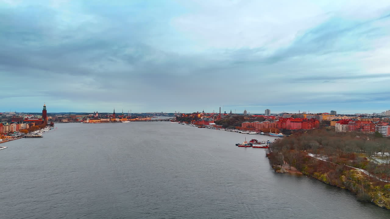 Vista del corso d'acqua degli edifici della città lungo il fiume sotto un cielo nuvoloso a Stoccolma. Gli edifici della città fiancheggiano le sponde di un ampio fiume in una fresca giornata a Stoccolma