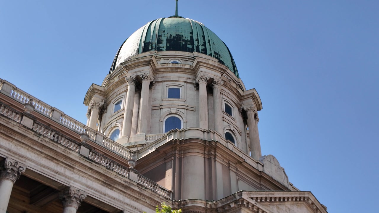 Slow tilt upward revealing the cupola of Buda Castle, highlighting decorative stonework and historic architecture
