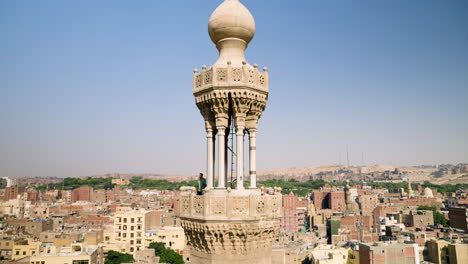 man at minaret tower of bab zuweila, gate in city walls of historic cairo in egypt. wide shot